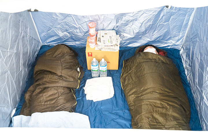 避難用テント（屋根なしBOXタイプ）の内部。寝袋2つと荷物を置いた様子
